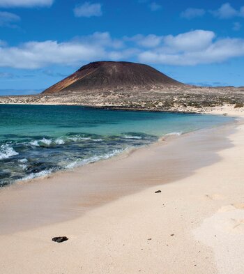 die Bucht Playa Francesa auf La Graciosa mit feinsandigem Strand und dem Montaña Amarilla im Hintergrund