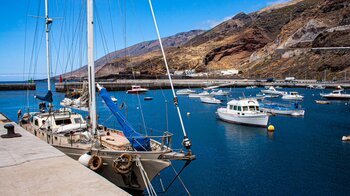 Segelboot vor der Kulisse der zum Meer hin abfallenden Berghänge am Puerto de la Estaca auf El Hierro