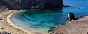 der Strand Playa de Papagayo auf Lanzarote mit türkiesgrünem Wasser und der Insel Fuerteventura im Hintergrund