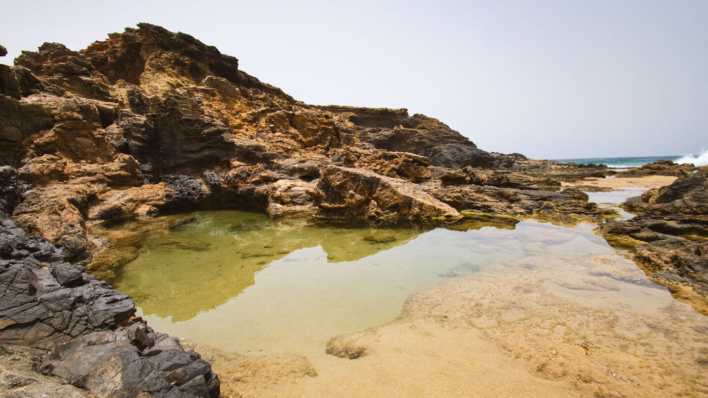 einige Meerwasserbecken liegen geschützt hinter Basaltformationen