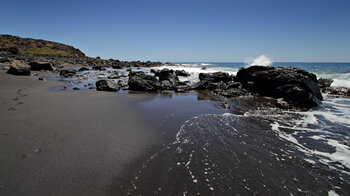 Blick entlang des schwarzen Sandstrands an der Playa del Inglés