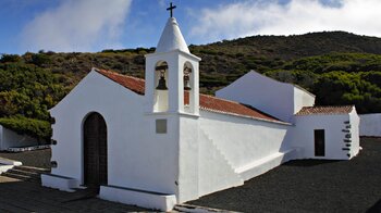 die strahlend weiße Ermita Virgen de los Reyes vor grün bewaldeten Hängen