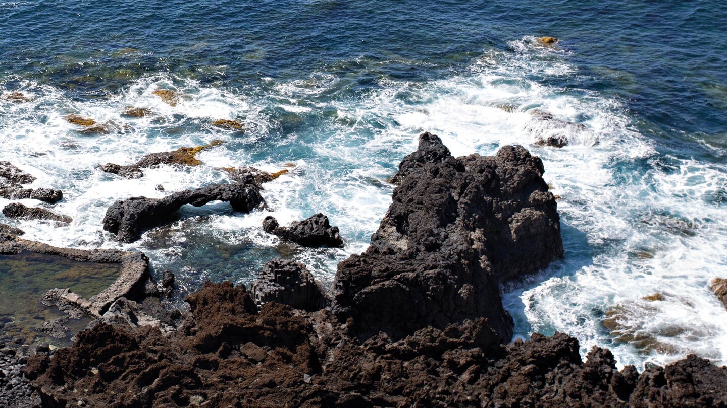 Blick vom Parkplatz auf skurrile Felsformationen und Felsbögen der wilden Bucht des Charco Azul auf El Hierro