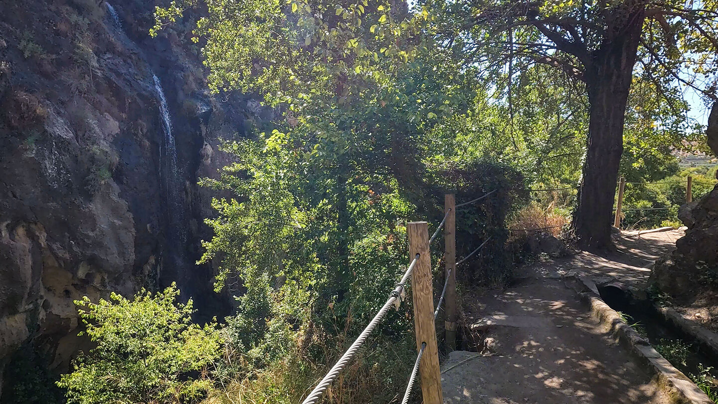 Wanderweg am Kanal mit seitlich herabstürzenden Wasserfall