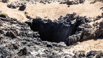 an den os Arcos de los Caletones auf La Graciosa fördert starker Wellengang Gischt aus einer ins Land versetzen Höhlenöffnung