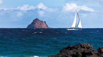 ein Segler zieht an der Insel Roque del Este im Chinijo Archipel bei Lanzarote vorbei