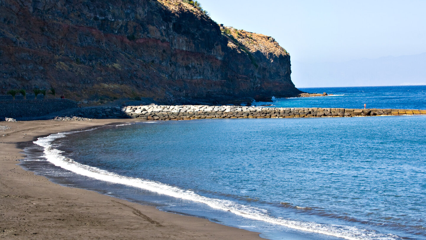 der saubere Strand der Playa de La Cueva auf La Gomera ist durch eine Hafenmole geschützt